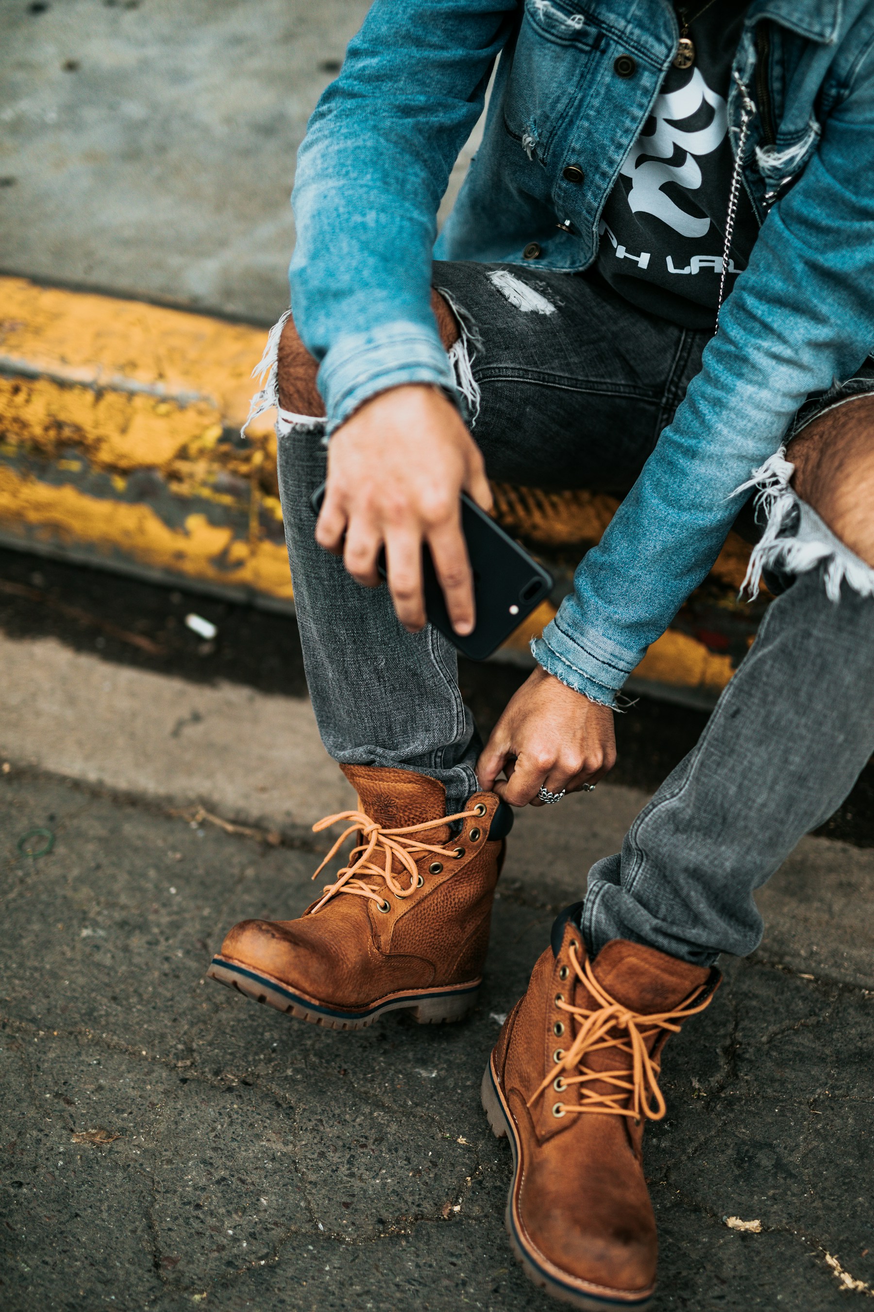 Distressed dark jeans worn with substantial tan lace-up boots