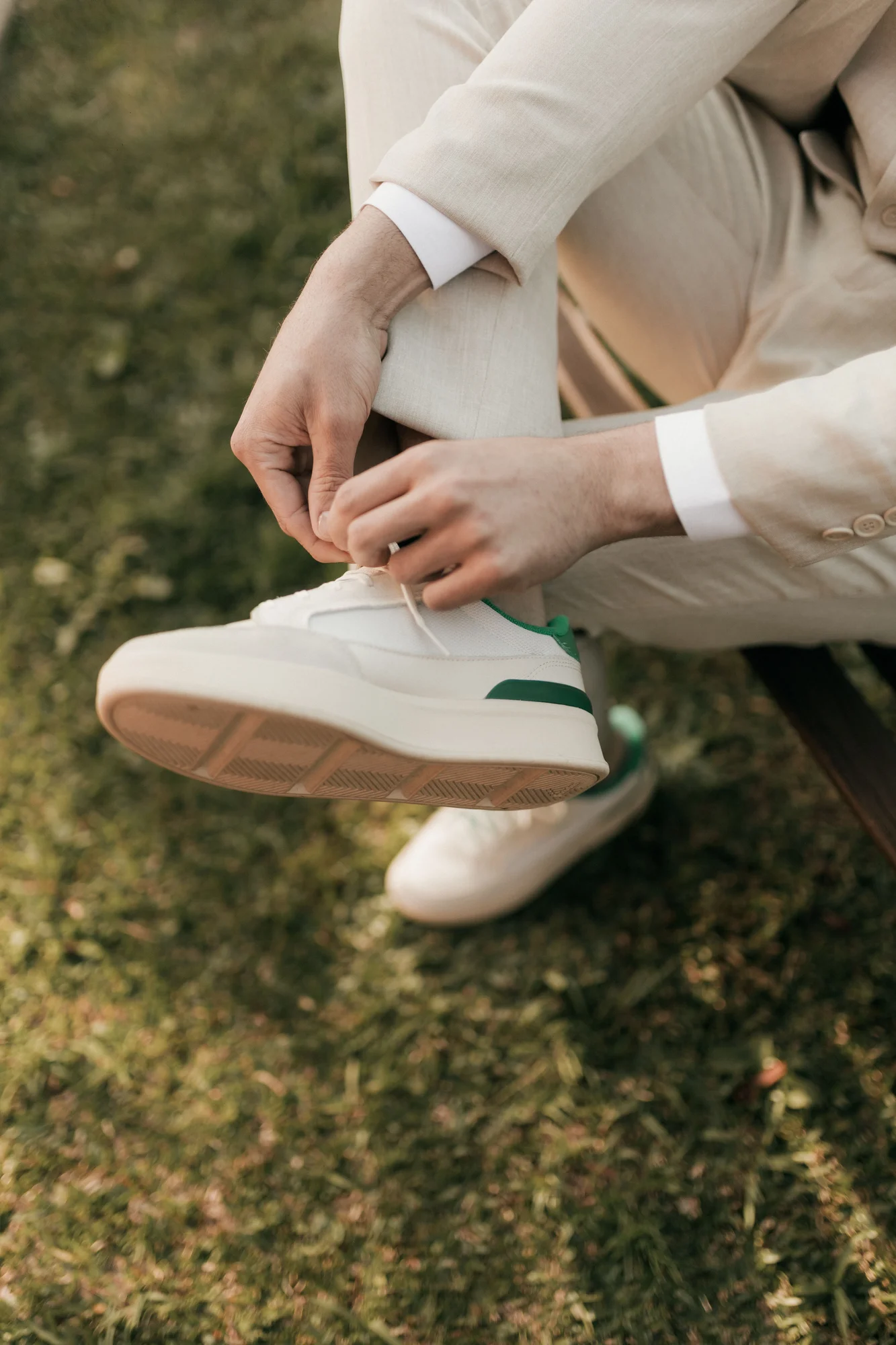 White sneakers being laced beneath cream trousers